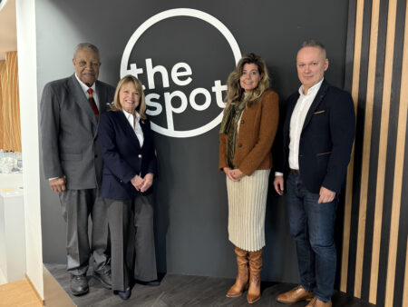 City and state officials pose in front of a sign that say, "The Spot."